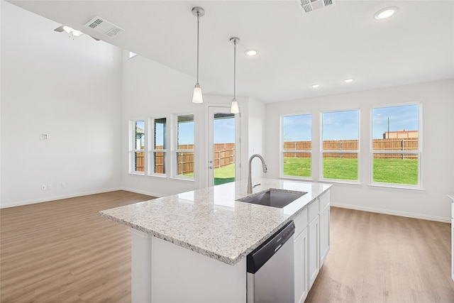 kitchen featuring a kitchen island with sink, light hardwood / wood-style flooring, sink, stainless steel dishwasher, and white cabinetry