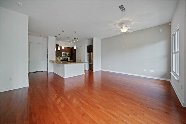 unfurnished living room with wood-type flooring, a wealth of natural light, and ceiling fan