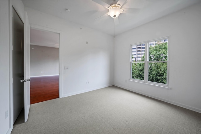 carpeted empty room featuring a ceiling fan and baseboards