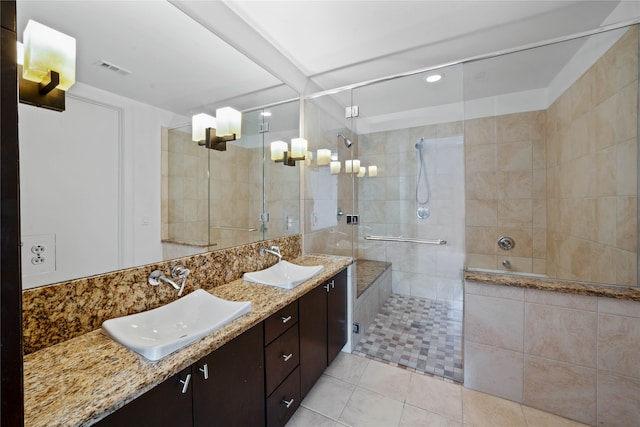 bathroom featuring a tile shower, double sink vanity, tile walls, and tile patterned flooring