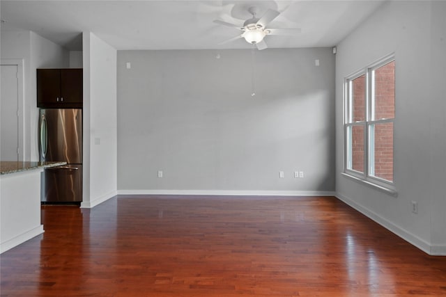 unfurnished room featuring a ceiling fan, dark wood-style flooring, and baseboards