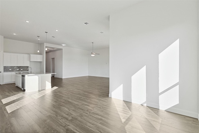 unfurnished living room featuring a sink, visible vents, wood finished floors, and a ceiling fan