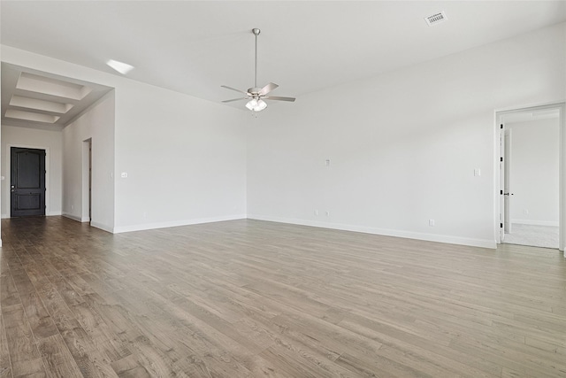 empty room featuring light wood finished floors, a ceiling fan, visible vents, and baseboards