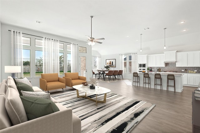 living room with lofted ceiling, visible vents, dark wood finished floors, and a ceiling fan