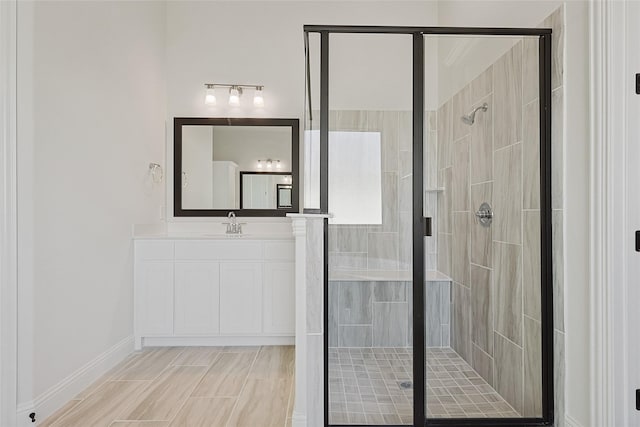 bathroom featuring a stall shower, vanity, and baseboards