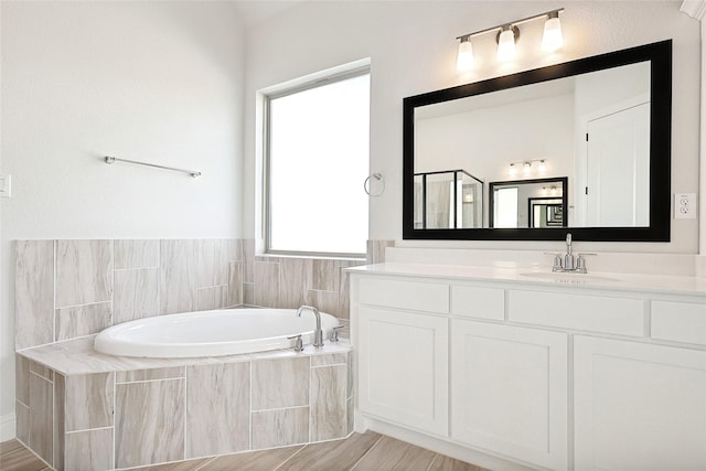 bathroom featuring a stall shower, a bath, and vanity