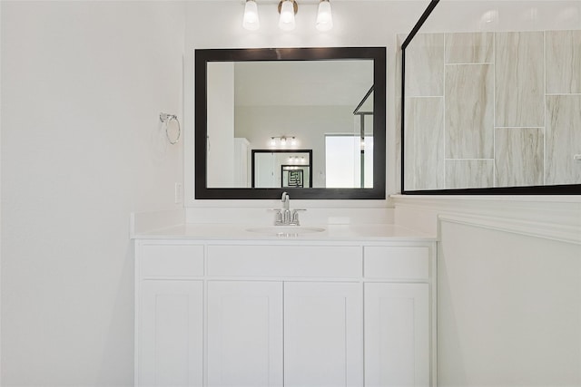 bathroom with a tile shower and vanity