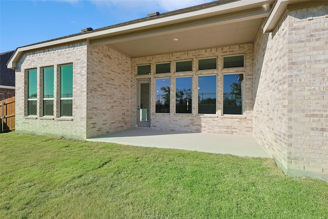 back of property featuring brick siding, a lawn, and a patio area