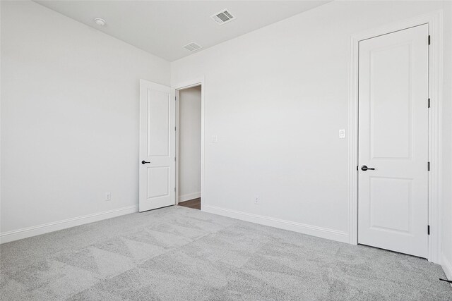 spare room with light carpet, visible vents, and baseboards