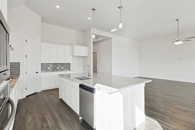 kitchen with light stone counters, stainless steel appliances, white cabinets, a kitchen island with sink, and a sink