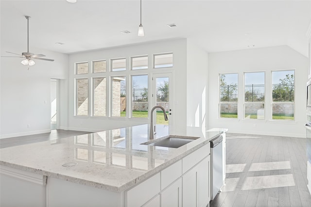 kitchen featuring light stone counters, a sink, white cabinetry, dishwasher, and decorative light fixtures