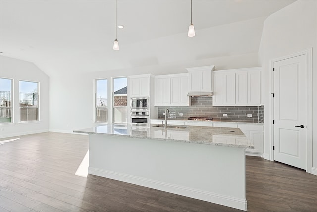 kitchen with stainless steel appliances, a sink, white cabinetry, hanging light fixtures, and a center island with sink