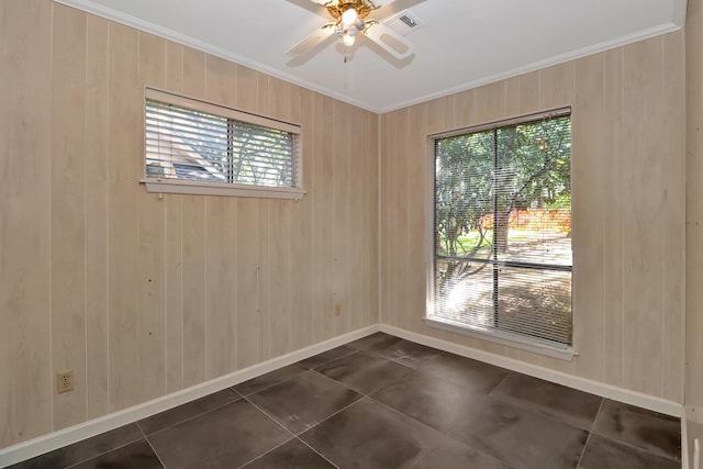 unfurnished room with ceiling fan, ornamental molding, a healthy amount of sunlight, and dark tile patterned floors