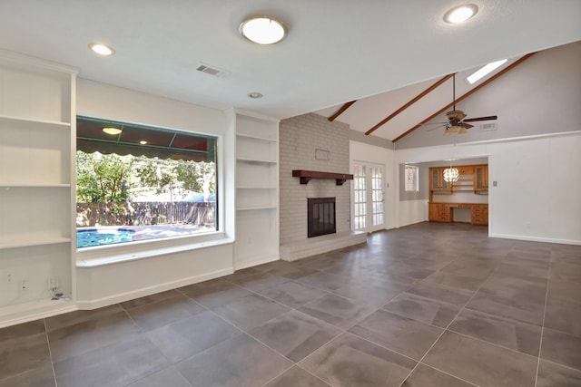 unfurnished living room featuring built in shelves, a skylight, a brick fireplace, dark tile patterned flooring, and ceiling fan