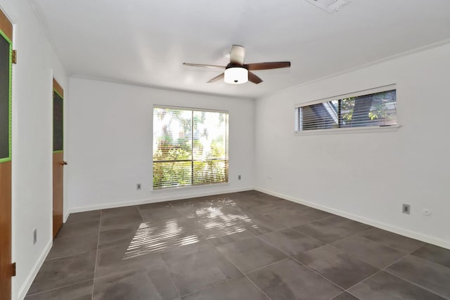 unfurnished room featuring dark tile patterned floors, ornamental molding, and ceiling fan