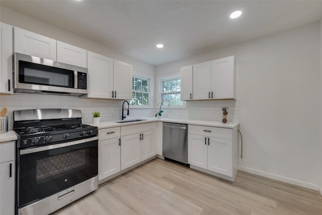 kitchen with light hardwood / wood-style flooring, appliances with stainless steel finishes, sink, and white cabinets