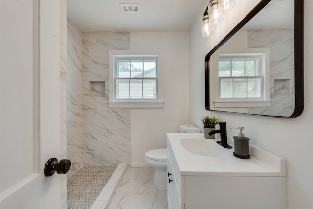 bathroom with vanity, toilet, and tiled shower