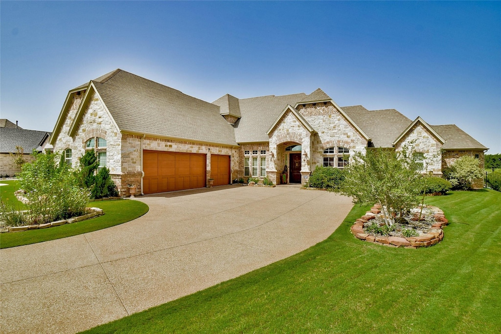 french country home featuring a garage and a front yard