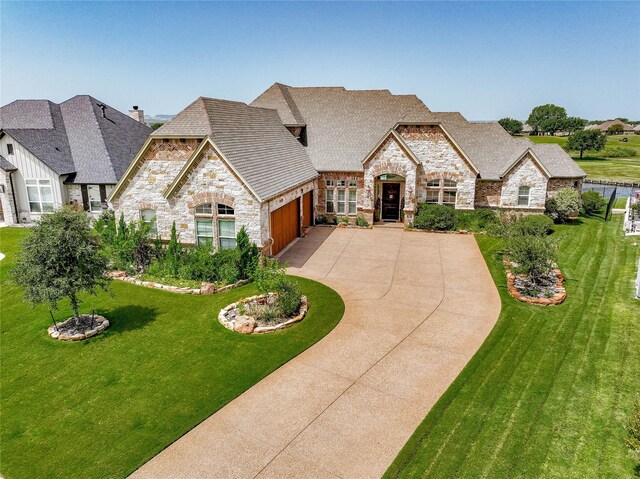 french country home featuring a front lawn and a garage