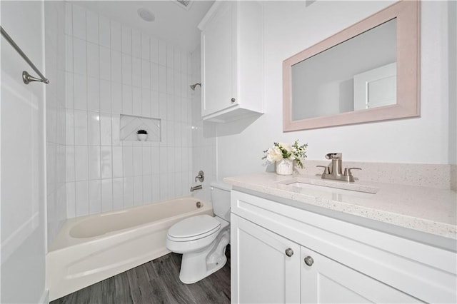 full bathroom with wood-type flooring, vanity, tiled shower / bath combo, and toilet