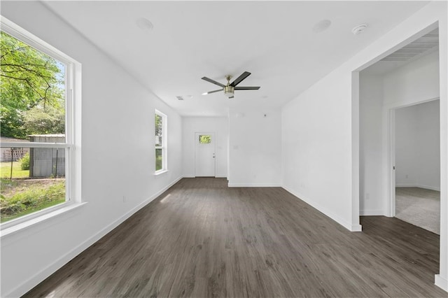 empty room featuring a healthy amount of sunlight, dark hardwood / wood-style flooring, and ceiling fan