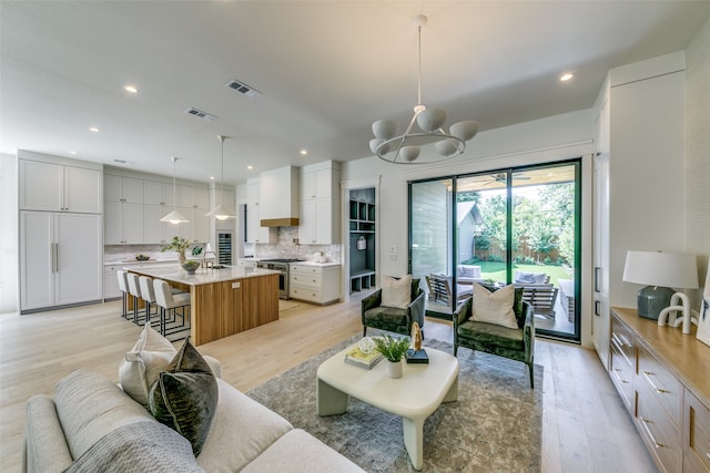 living room with a notable chandelier, sink, and light wood-type flooring