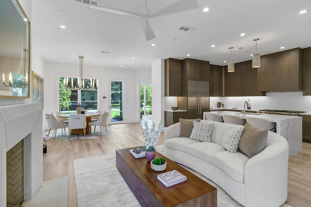 living room with sink, light hardwood / wood-style flooring, a notable chandelier, and a wealth of natural light