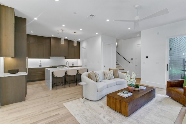 living room with ceiling fan, sink, and light hardwood / wood-style floors