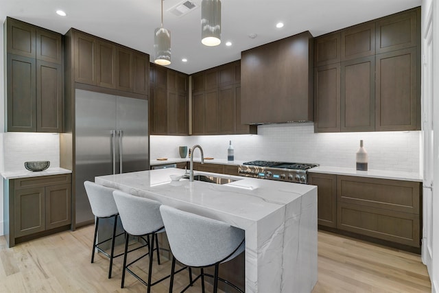 kitchen with sink, light hardwood / wood-style floors, decorative backsplash, and light stone countertops