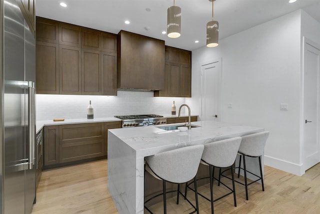 kitchen with light hardwood / wood-style floors, tasteful backsplash, sink, stainless steel built in refrigerator, and stove