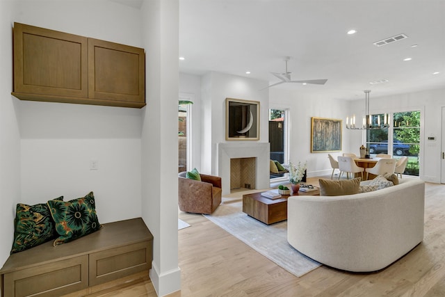 living room with ceiling fan with notable chandelier and light hardwood / wood-style floors