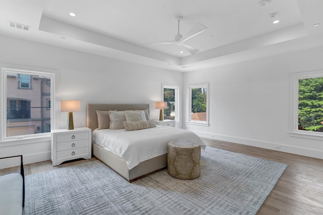 bedroom featuring a tray ceiling, ceiling fan, and light hardwood / wood-style floors