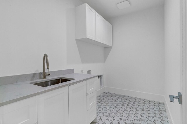 laundry room with sink, electric dryer hookup, light tile patterned floors, and cabinets