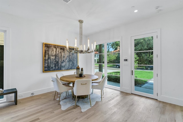 dining room featuring light wood-type flooring, plenty of natural light, and a notable chandelier