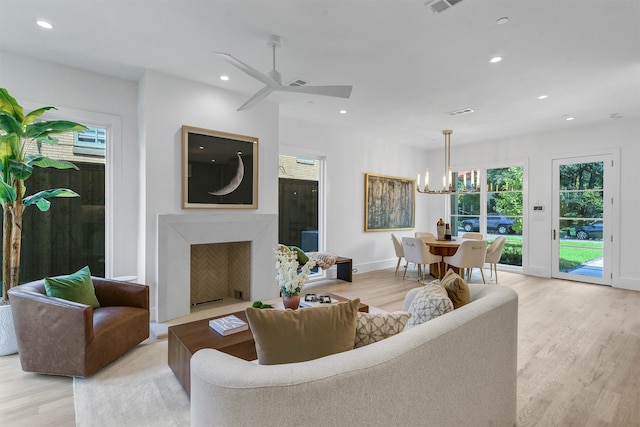 living room featuring light wood-type flooring and ceiling fan with notable chandelier