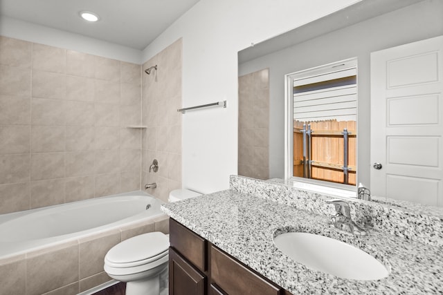 full bathroom featuring vanity, tiled shower / bath combo, and toilet