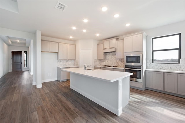 kitchen with sink, backsplash, appliances with stainless steel finishes, and hardwood / wood-style floors