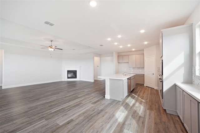 kitchen featuring gray cabinets, tasteful backsplash, ceiling fan, a kitchen island, and light hardwood / wood-style floors