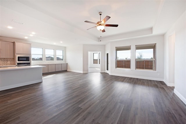 unfurnished living room featuring dark hardwood / wood-style floors, a raised ceiling, and ceiling fan