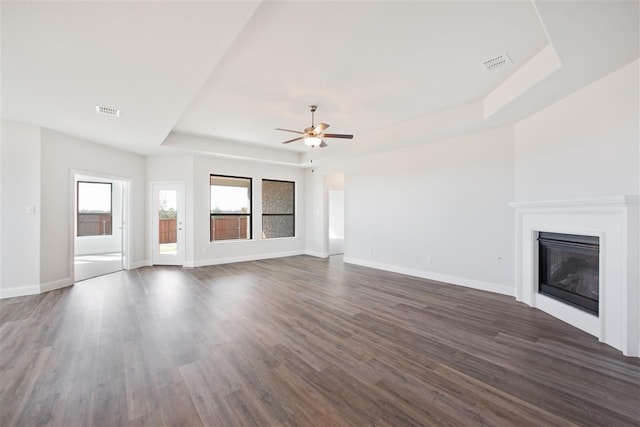 unfurnished living room featuring ceiling fan, a tray ceiling, and hardwood / wood-style floors