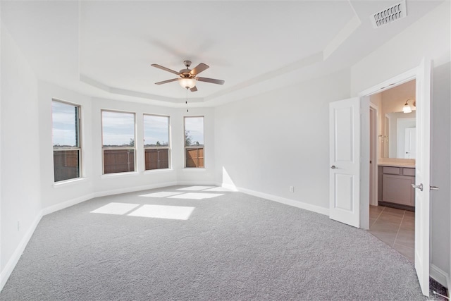 spare room featuring ceiling fan, light colored carpet, and a tray ceiling