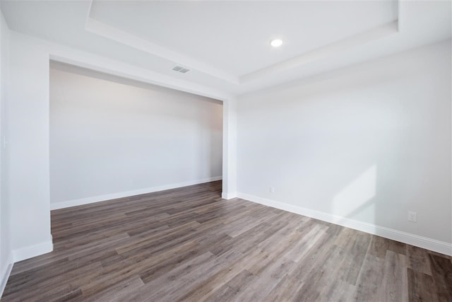 unfurnished room featuring hardwood / wood-style flooring and a tray ceiling