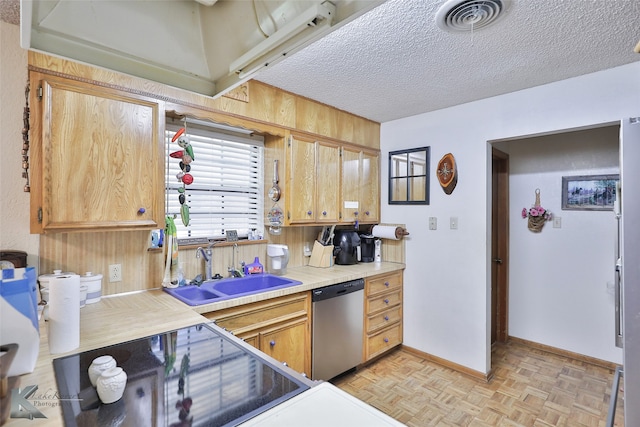 kitchen with light parquet floors, stainless steel dishwasher, a textured ceiling, and sink