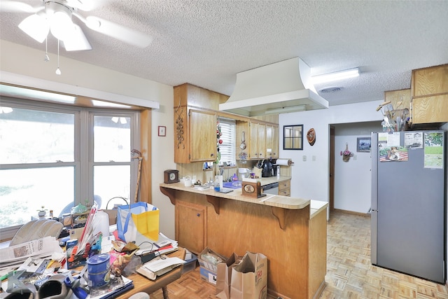 kitchen featuring light parquet floors, fridge, kitchen peninsula, and plenty of natural light