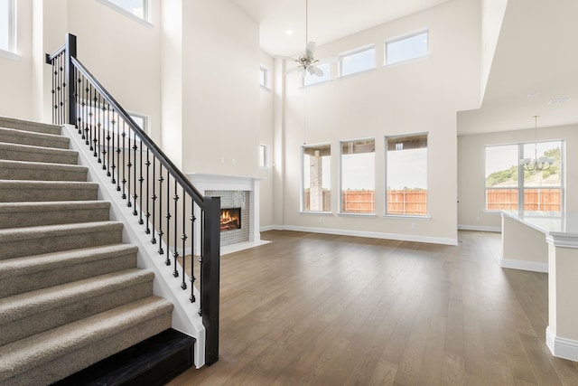 foyer entrance with hardwood / wood-style flooring, a towering ceiling, and ceiling fan