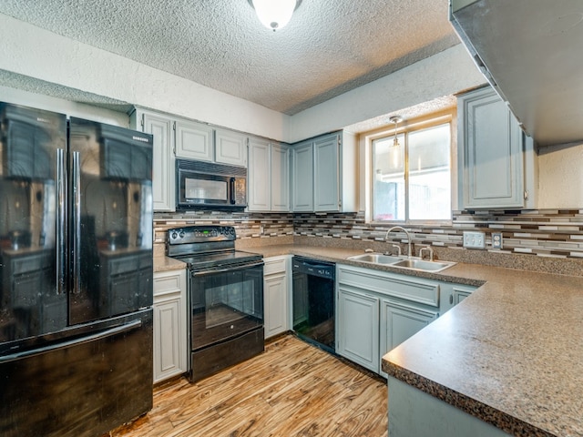 kitchen featuring backsplash, black appliances, light hardwood / wood-style flooring, and sink