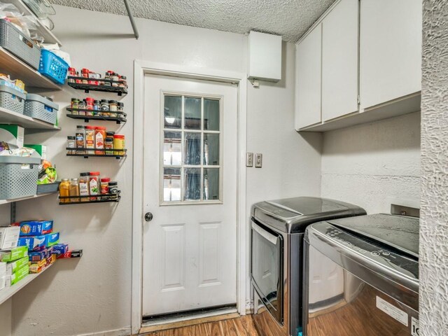 laundry area with washer and clothes dryer, hardwood / wood-style floors, cabinets, and a textured ceiling