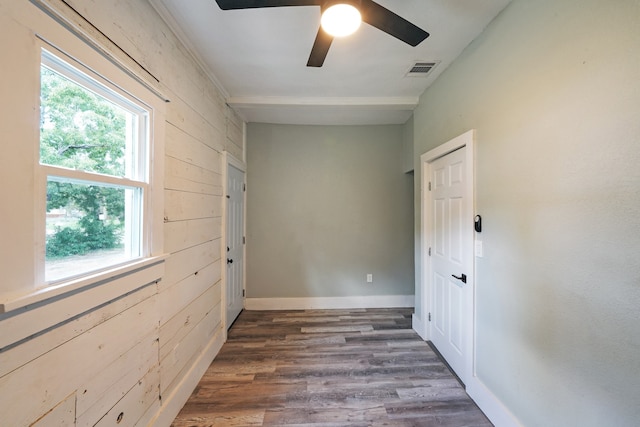 empty room featuring ceiling fan, dark hardwood / wood-style flooring, and wood walls