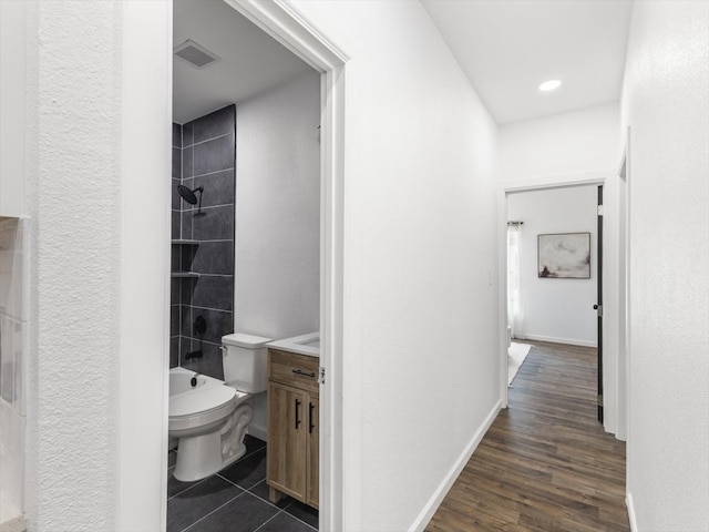 full bathroom featuring vanity, tiled shower / bath combo, wood-type flooring, and toilet