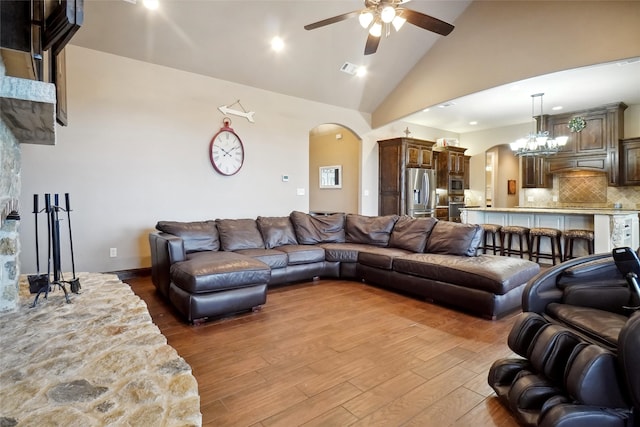 living room featuring high vaulted ceiling, ceiling fan with notable chandelier, and hardwood / wood-style floors